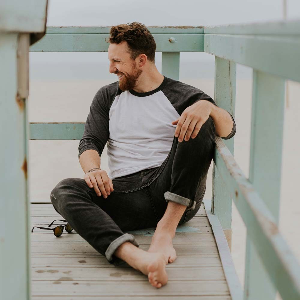 Man in jeans sitting on boardwalk